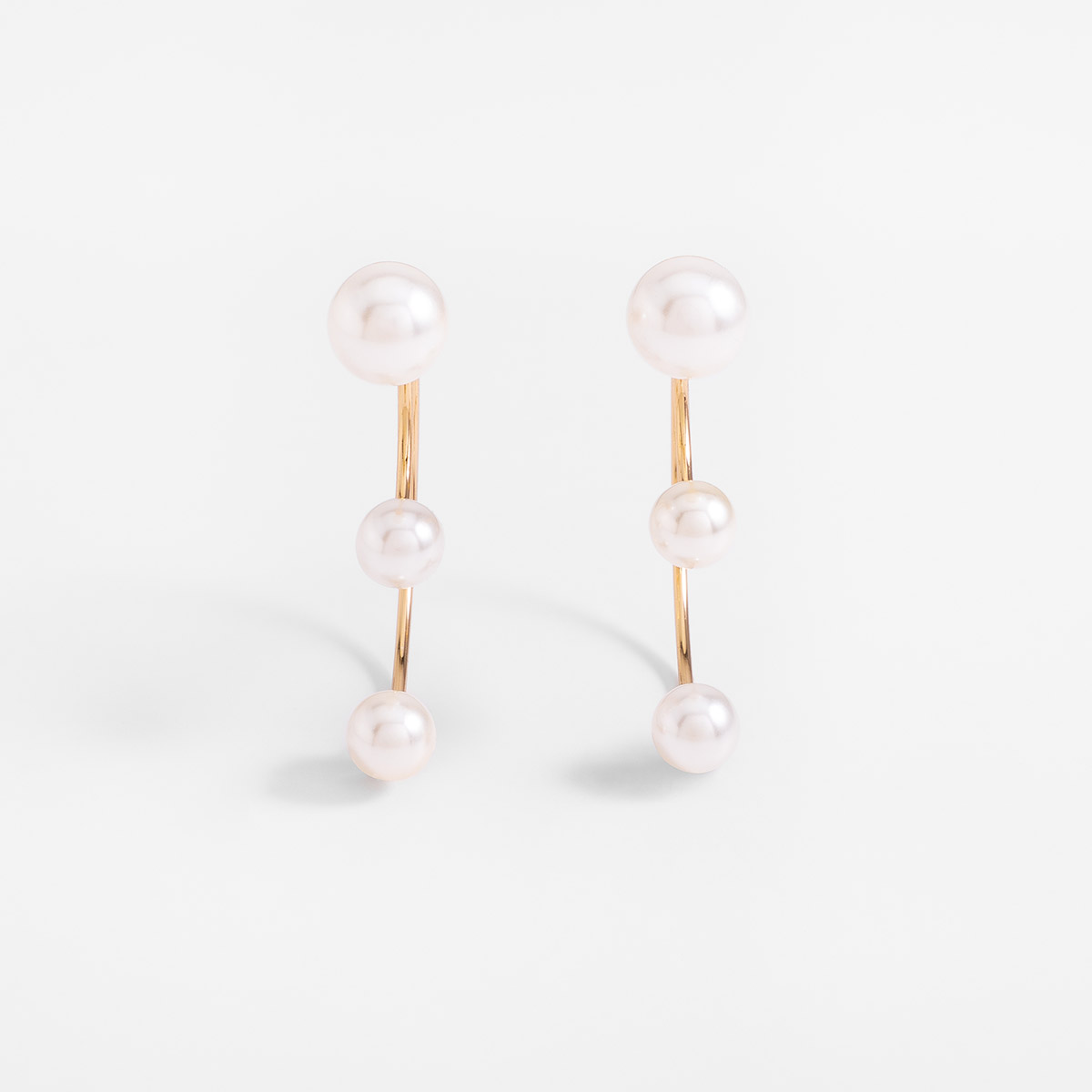 Aretes poste en baño de oro con esferas tipo perla diseño curvo