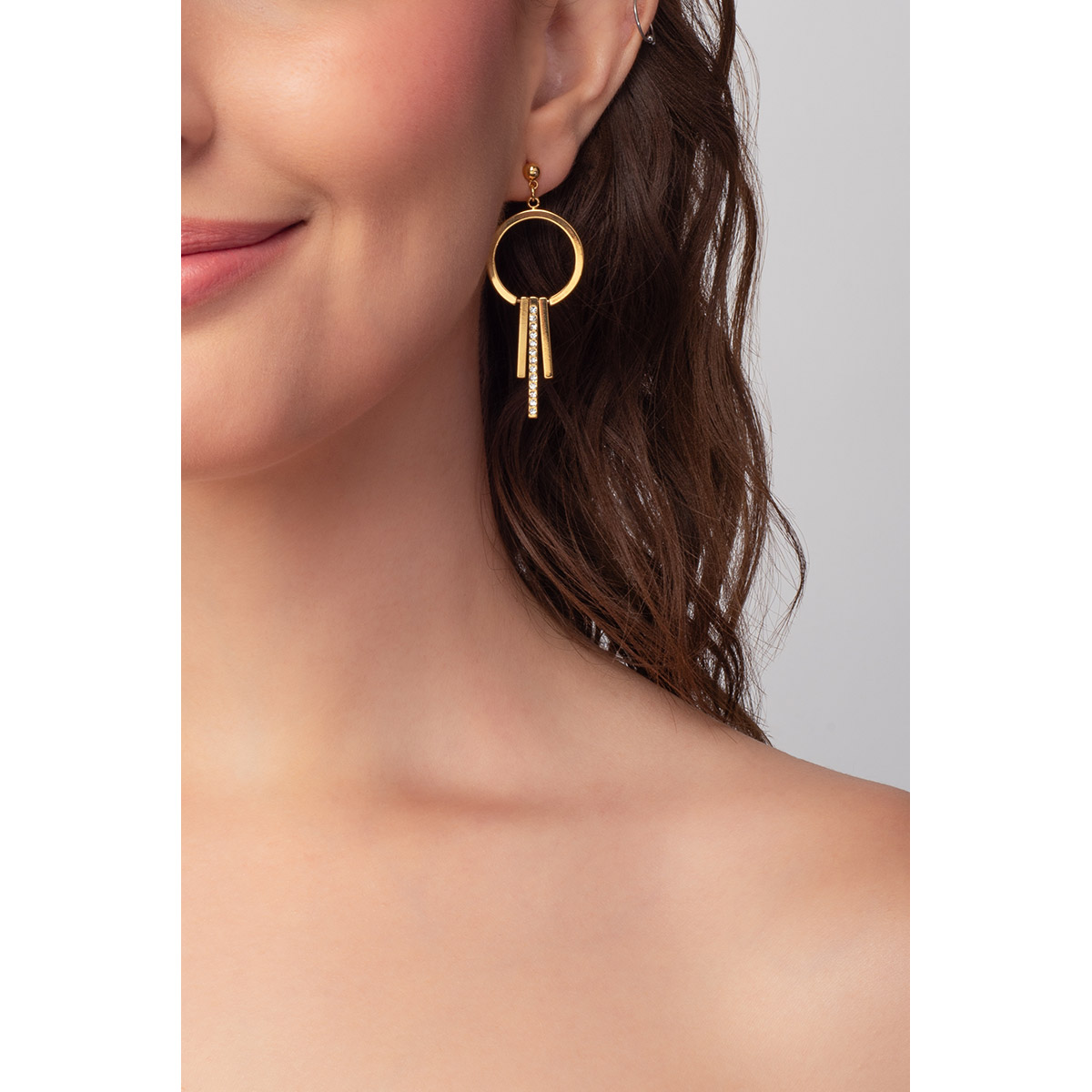 Aretes en baño de oro, con diseño en forma de aro dorado, complementado con tres barras colgantes incrustadas con piedras en tono cristal.
-        Aretes largos
-        Poste
-        Baño de Oro 18k
-        Piedras en tono cristal
