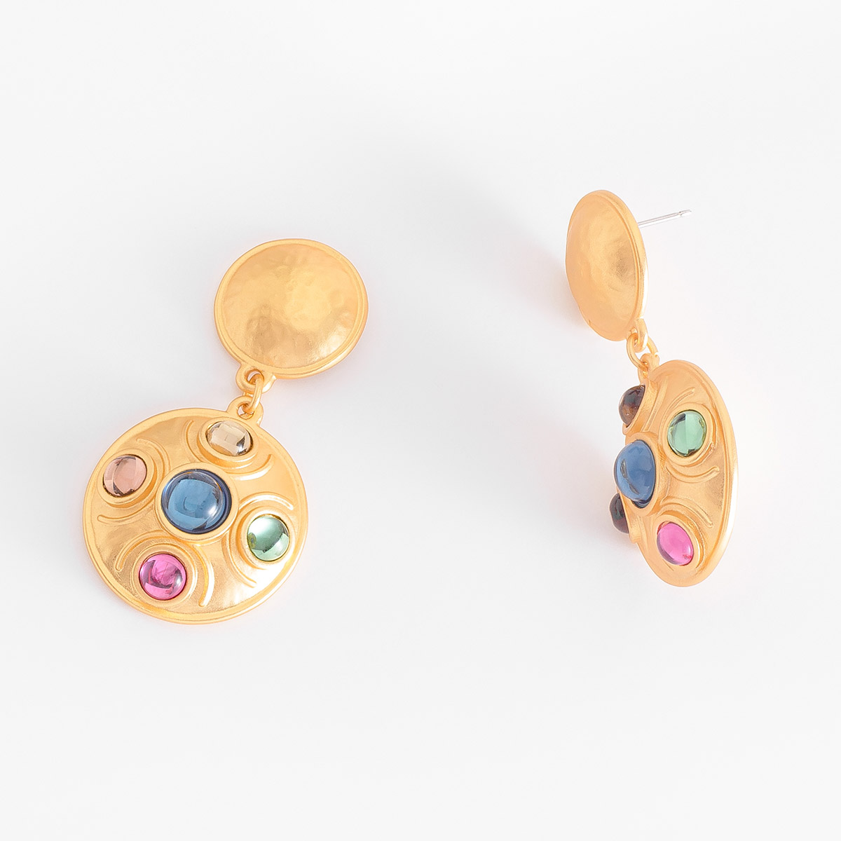 Aretes con un diseño vibrante de círculos dorados, uno de ellos texturizado y el otro con un diseño de piedras, una al centro y cuatro en puntos cardinales de tonos azul, verde claro, rosa, café y cristal.
-        Aretes grandes
-        Poste
-        Baño de Oro 18k
-        Piedras en tono azul, verde claro, rosa, café y cristal
