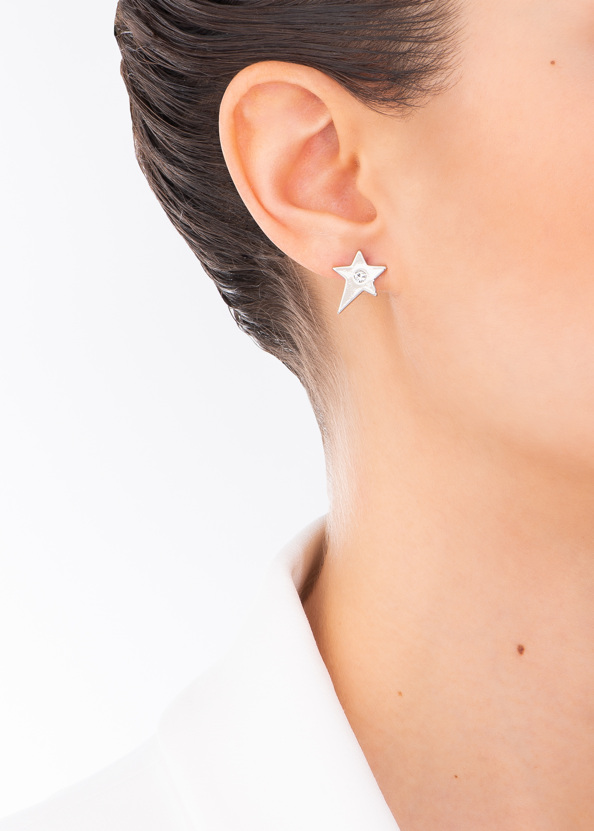 Aretes en baño de platino, con diseño de estrella de cinco puntos asimétrica. Incrustada al centro con una piedra en tono cristal.
-        Aretes chicos
-        Poste
-        Baño de Platino
-        Piedra en tono cristal