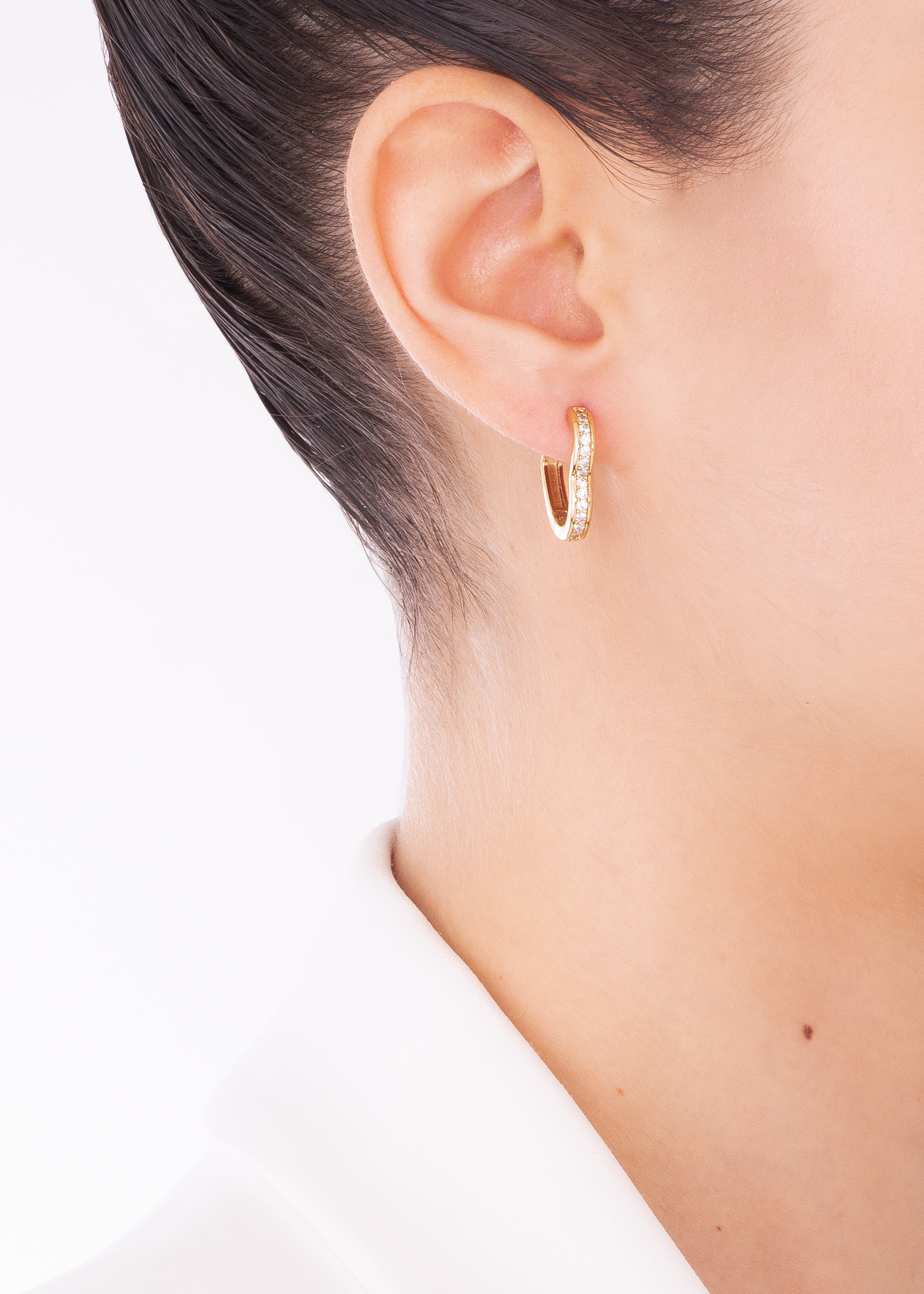 
Hermosos aretes en forma de corazón, con una fila incrustada de piedras en tono cristal. 
-        Aretes con poste
-        Baño de Oro 18k
-        Piedras en tono cristal
