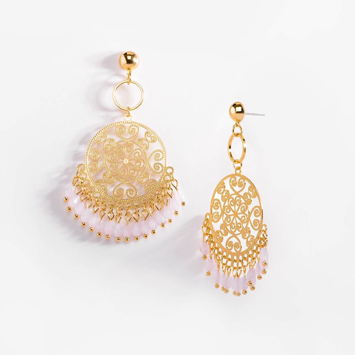 Extravagantes aretes en forma circular con patrones tipo filigranas, evocando detalles florales, arabescos y de corazones. En la parte inferior cuelgan delicadas piedras en tono rosa, añadiendo movimiento a la pieza.
-        Aretes con poste
-        Baño de Oro 18k
-        Piedras en tono rosa.
