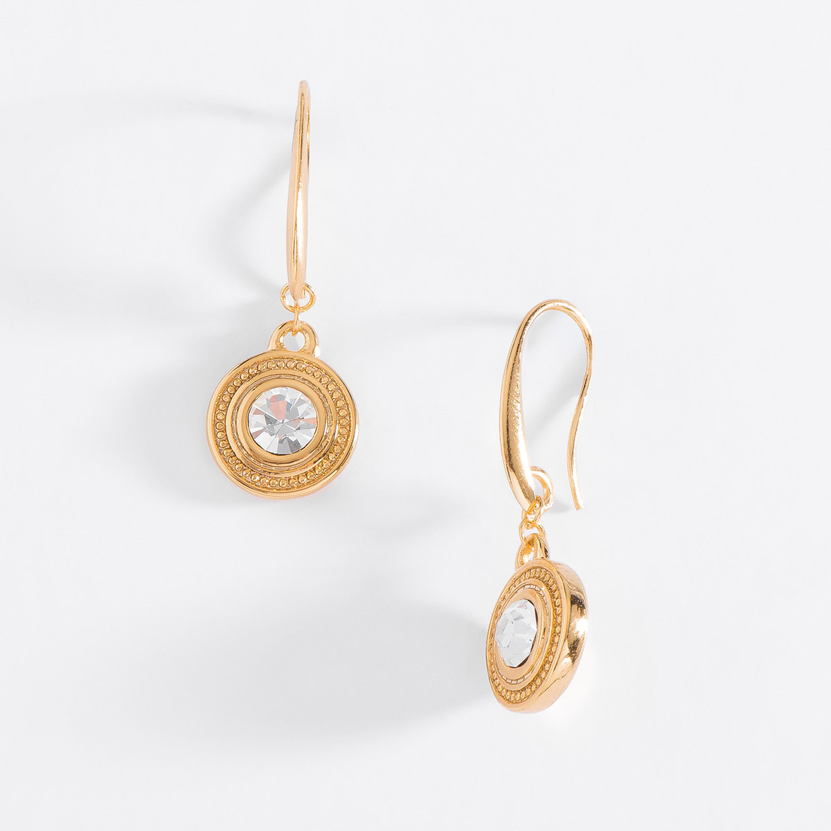 Aretes en baño de oro, con un colgante circular que incluye una piedra en tono cristal incrustada al centro. El borde del colgante tiene un delicado detalle texturizado.
-        Aretes medianos
-        Garfio
-        Baño de Oro
-        Piedras en tono cristal
