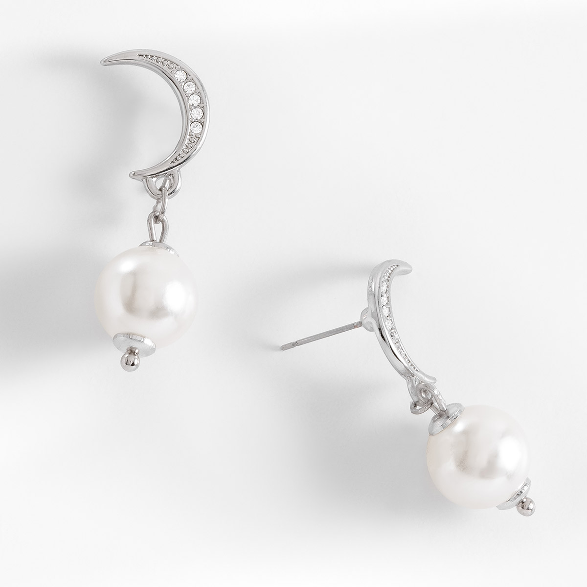 Aretes en forma de media luna, con poste, en baño de platino, con perla en tono crema.