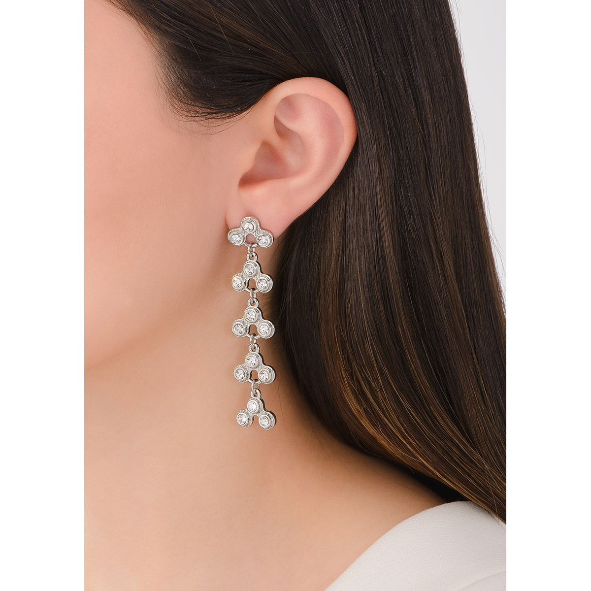 Aretes largos en baño de platino con diseño de triadas con piedras en tono cristal.
-        Aretes largos con poste
-        Baño de platino