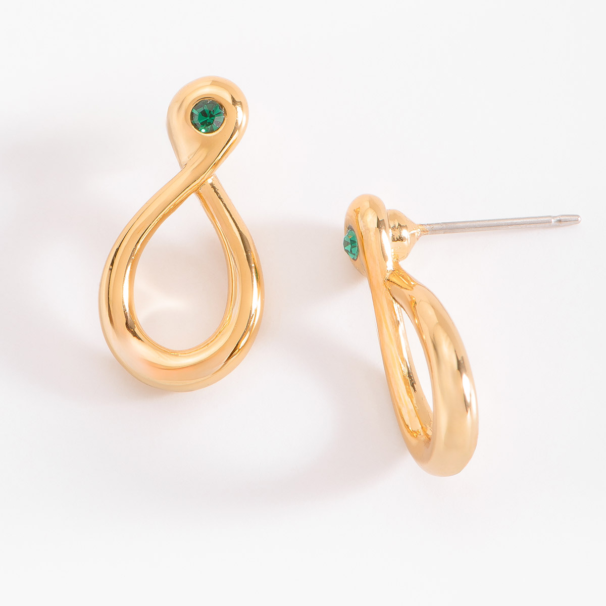 Aretes en baño de oro, con una forma de líneas fluidas y curvas que crea una silueta en forma de infinito. Cuenta con una piedra esmeralda incrustada.
-        Aretes chicos
-        Poste
-        Baño de Oro 18k
-        Piedra en tono esmeralda
