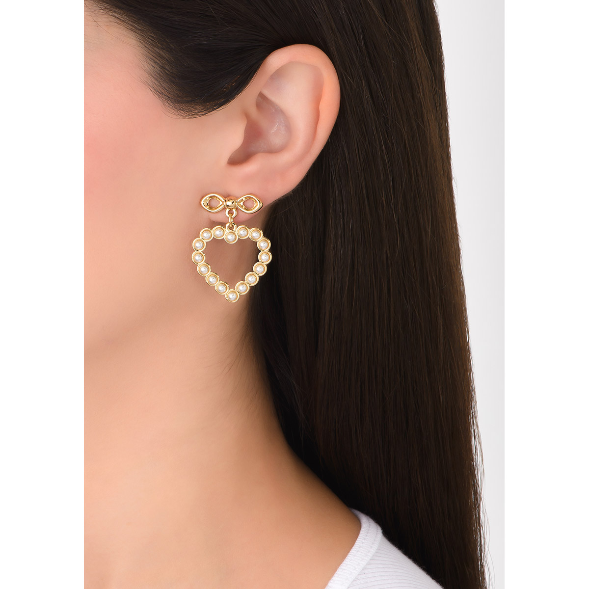 Un diseño encañador convive en estos aretes, con una forma de moño de donde cuelga un dije en forma de corazón, incrustado alrededor por perlas en tono cream, todo en baño de oro. Combínalo con tu collar y pulsera.
-       Aretes medianos
-        Poste
-        Baño de Oro 18k
-        Perlas en tono cream
