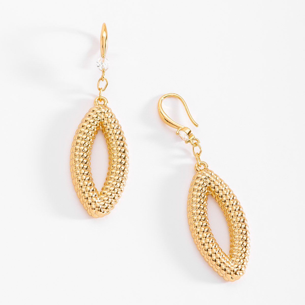 Aretes en baño de oro, con una piedra Diamonice en tono cristal de donde cuelga una forma ovalada texturizada. Combínalos con tu collar y pulsera.
-        Aretes largos
-        Garfio
-        Baño de Oro
-        Diamonice en tono cristal
