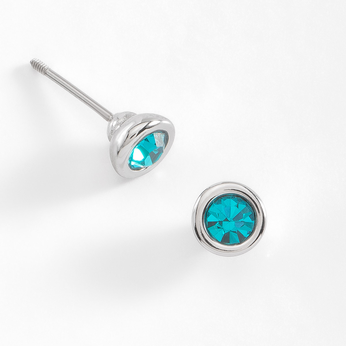 Coquetos aretes en forma de botón, con una piedra incrustada en tono aqua, en baño de platino.
-        Aretes chicos
-        Poste
-        Baño de Platino
-        Piedra en tono aqua
