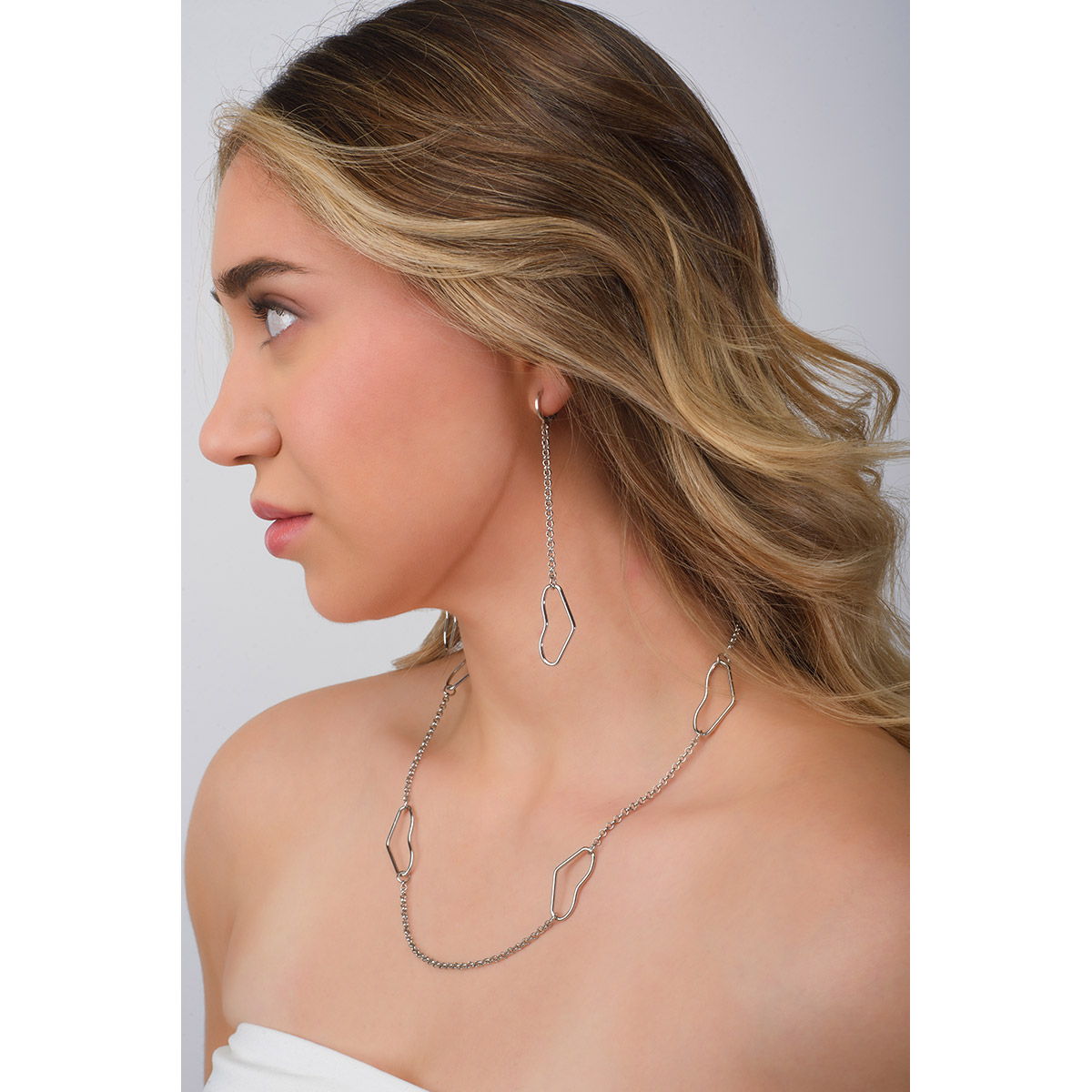 Aretes con corazones colgantes entrelazados por eslabones pequeños, todo en baño de Platino. Combínalos con tu collar.
-        Aretes largos
-        Patente
-        Baño de Platino