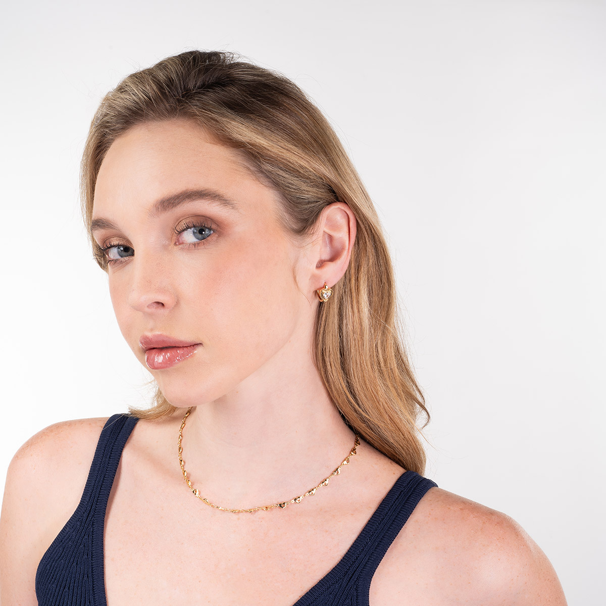 Aretes en baño de oro con corazón y piedra en toque brillante