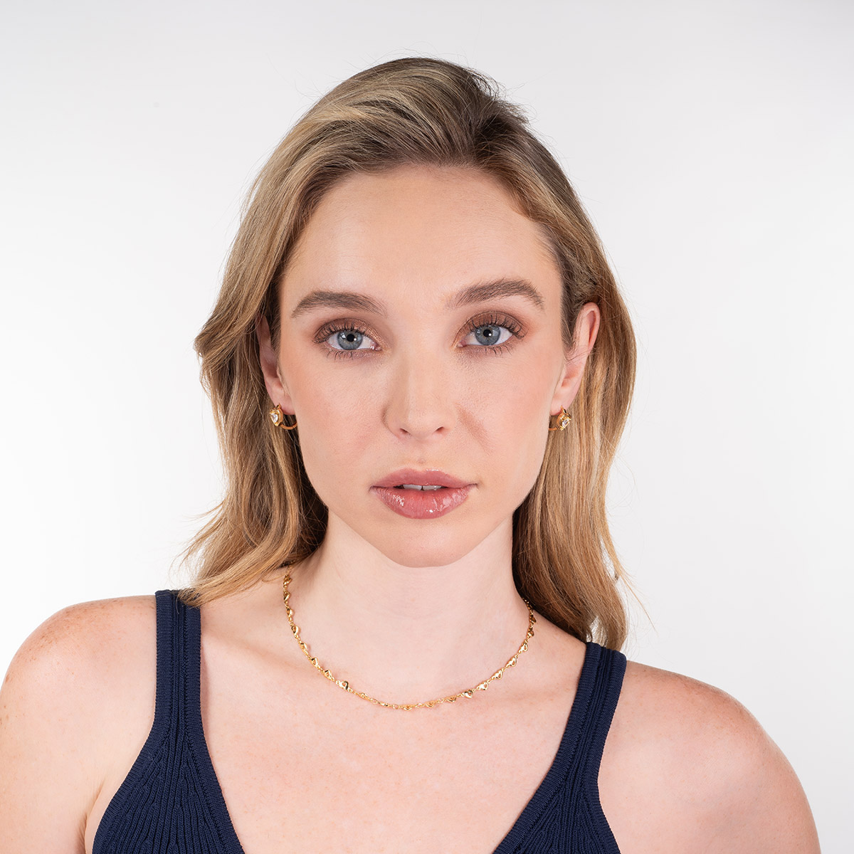 Aretes en baño de oro con corazón y piedra en toque brillante