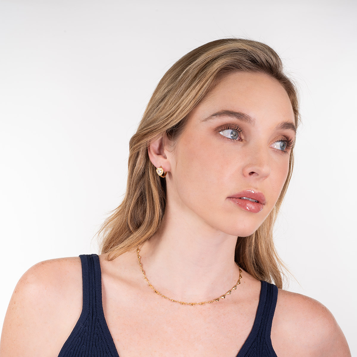 Aretes en baño de oro con corazón y piedra en toque brillante