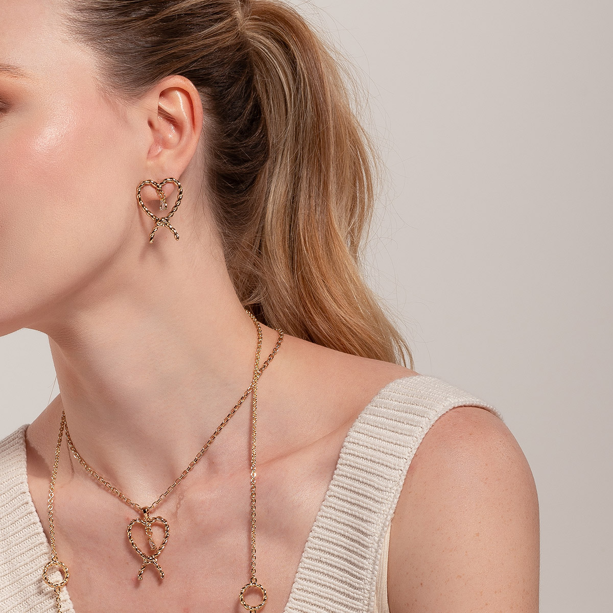 Aretes en baño de oro forma lazo y piedra brillante poste
