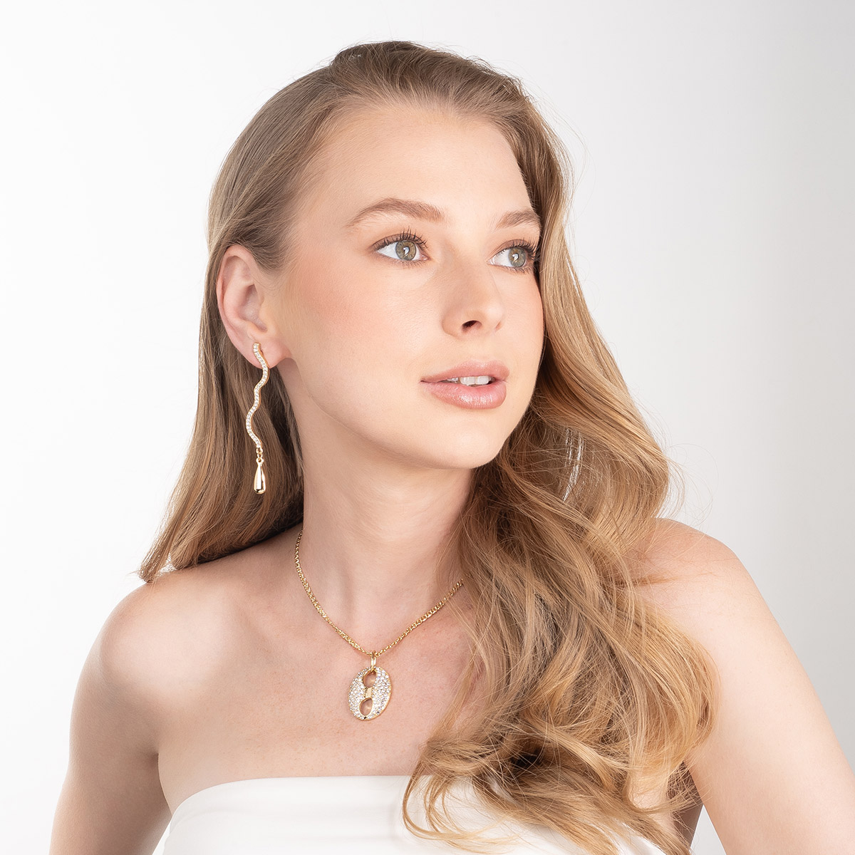 Aretes en baño de oro forma ondulada y piedras brillante