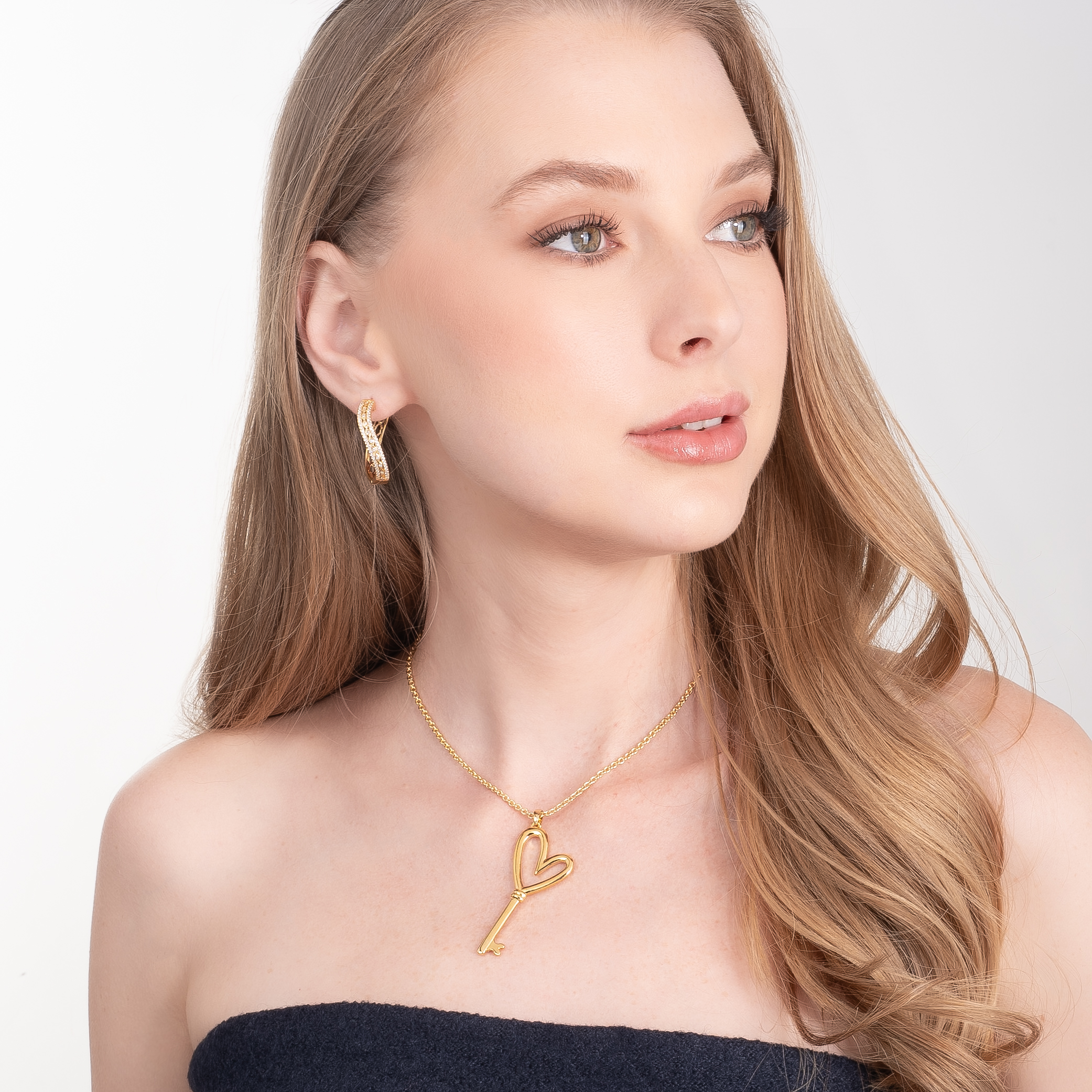 Aretes en baño de oro con piedras en tono cristal diseño cruzado