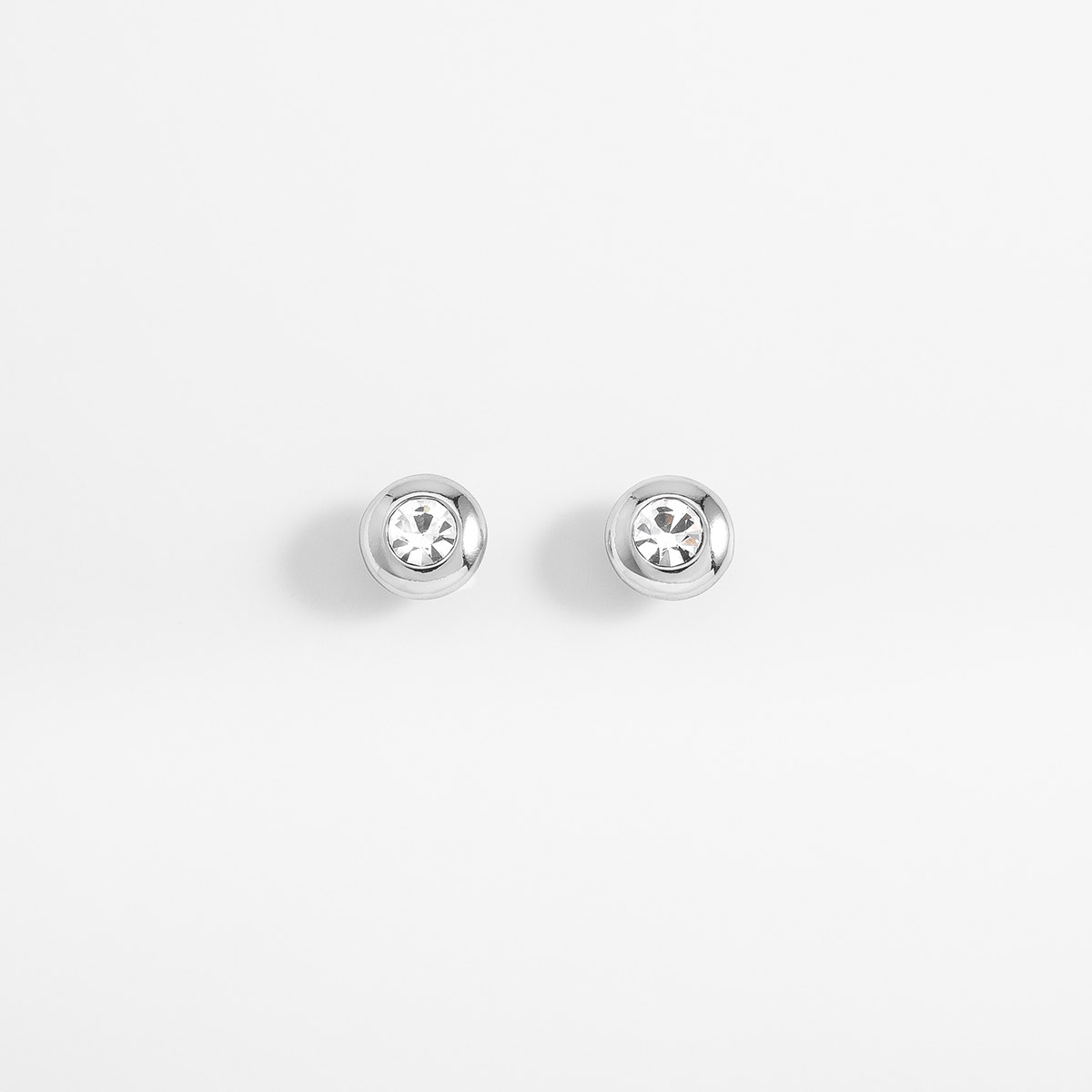 Aretes en baño de rodio con piedra en tono cristal diámetro 1 cm