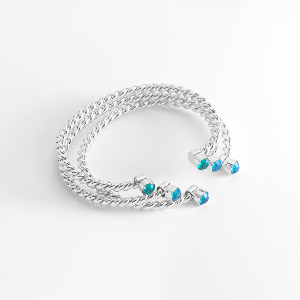 Set de 3 pulseras en baño de platino, con múltiples bandas entrelazadas con textura entrelazada, que forman una estructura abierta y ajustable. Cada extremo de las bandas está incrustado con piedras en tonos azules brillantes.
-        Set de tres pulseras
-        Medida ajustable
-        Baño de Platino
-        Piedras en tono azul
