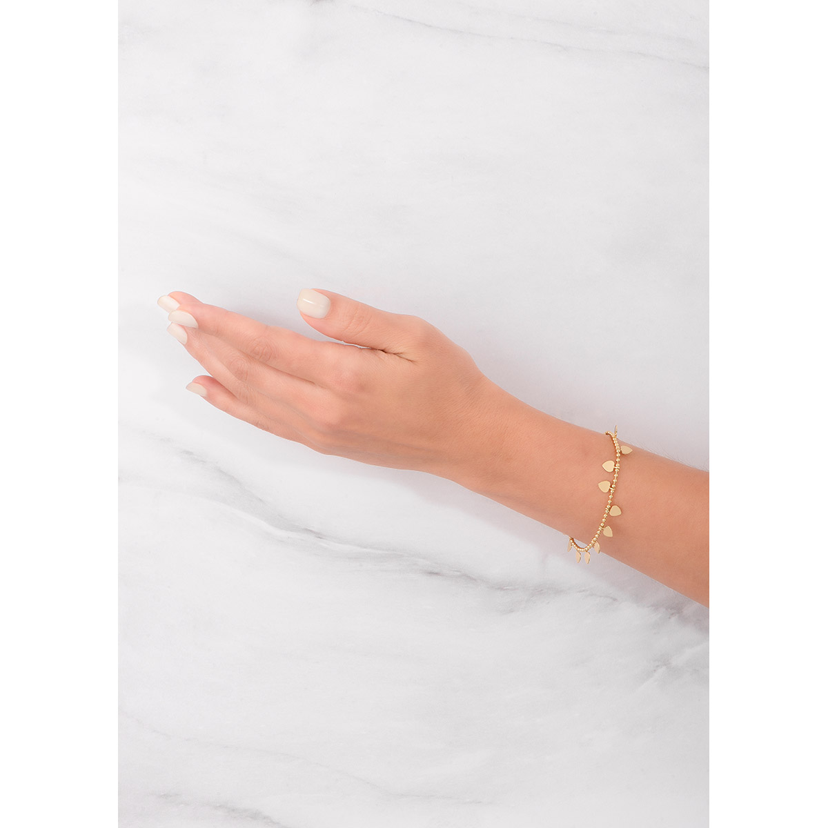 Pulsera compuesta por una cadena de esferas doradas, de donde cuelgan pequeños dijes en forma de corazón, todo en baño de oro. 
-        Pulsera
-        21 cm 
-        Baño de Oro 18k
