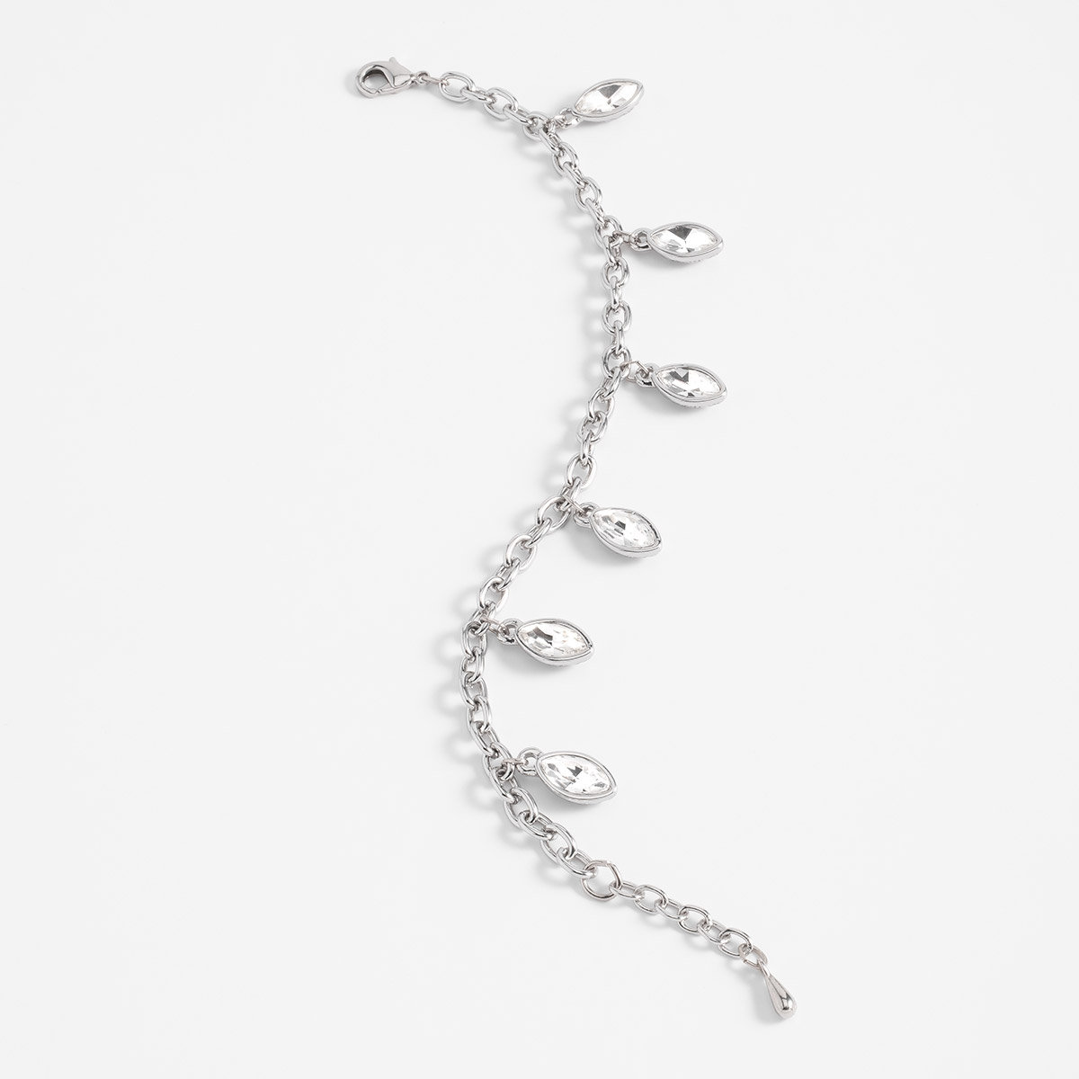 Pulsera en baño de rodio con dijes alargados y piedras en tono cristal.