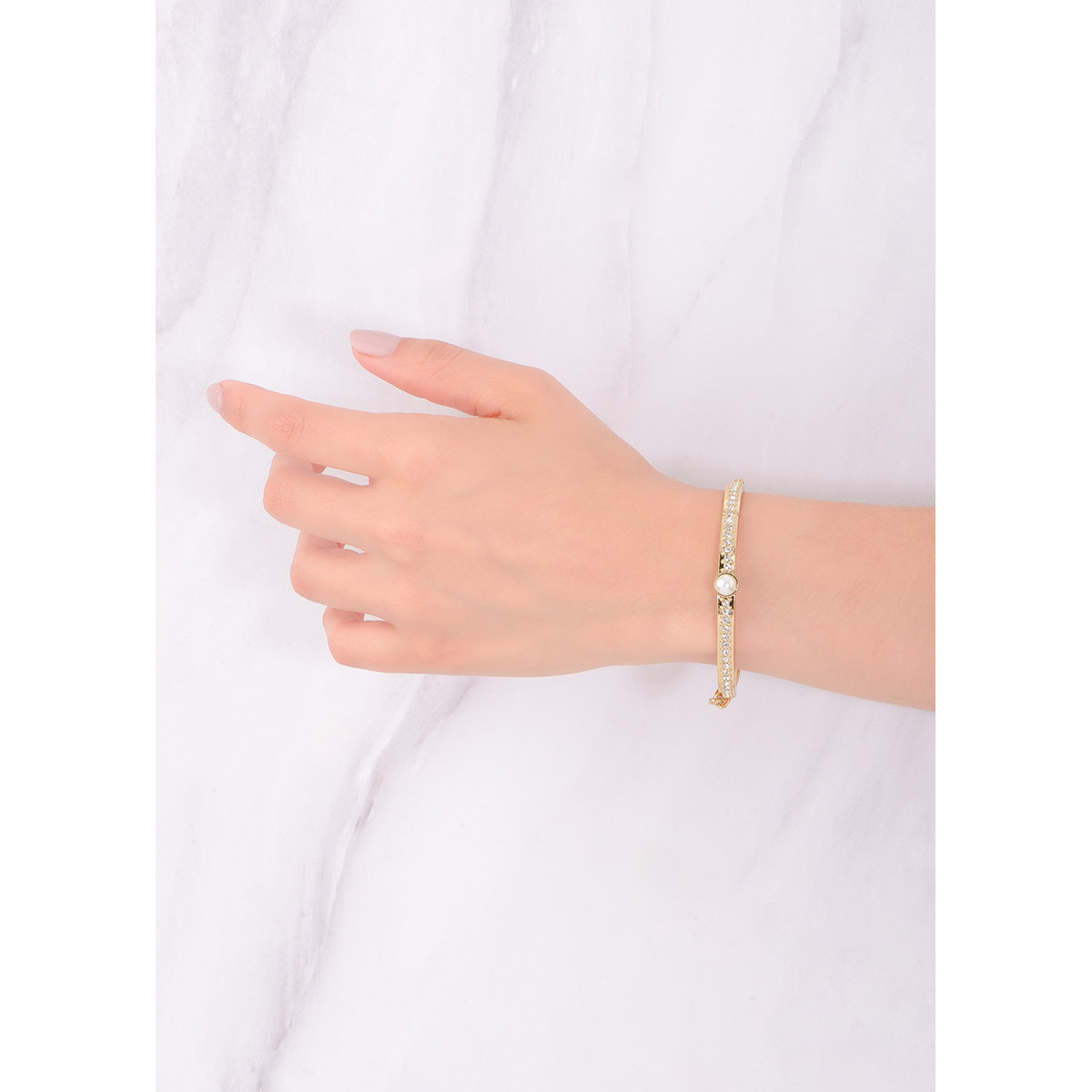 Sofisticado brazalete ajustable en baño de oro 18k, con un diseño especial; al centro una perla en tono crema, acompañada a los lados con piedras en tono cristal. Combínalo con tu collar y aretes.
-        Pulsera
-        Medida Ajustable
-        Baño de Oro 18k
-        Perla en tono crema
-        Piedras en tono cristal
