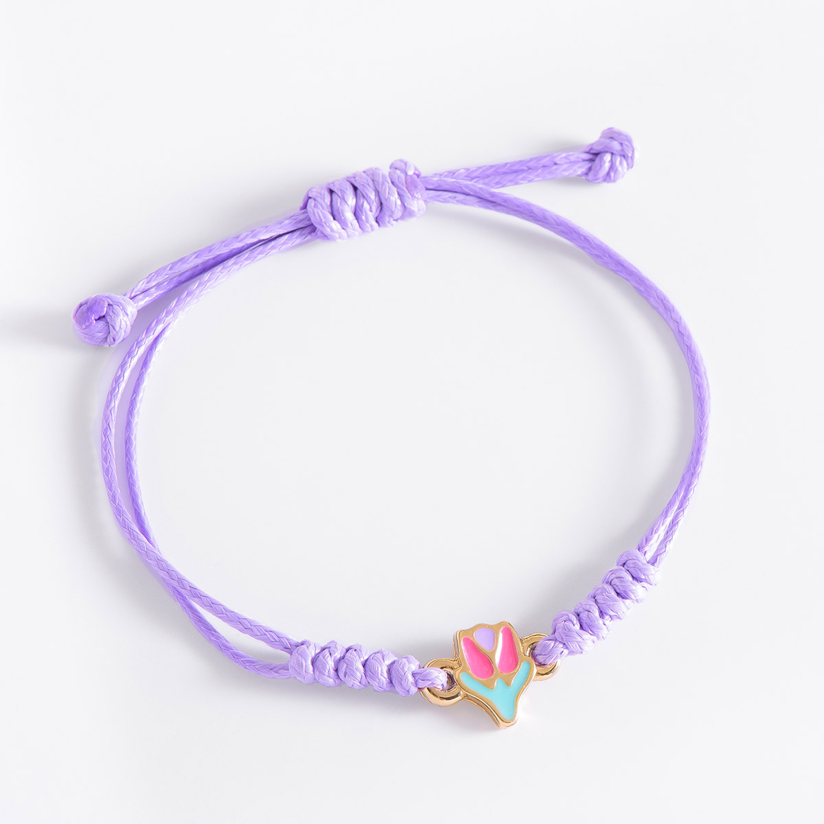 Pulsera ajustable con figurita de flor, en baño de oro, con cordón lila, con esmalte en tonos fucsia, morado y aqua.