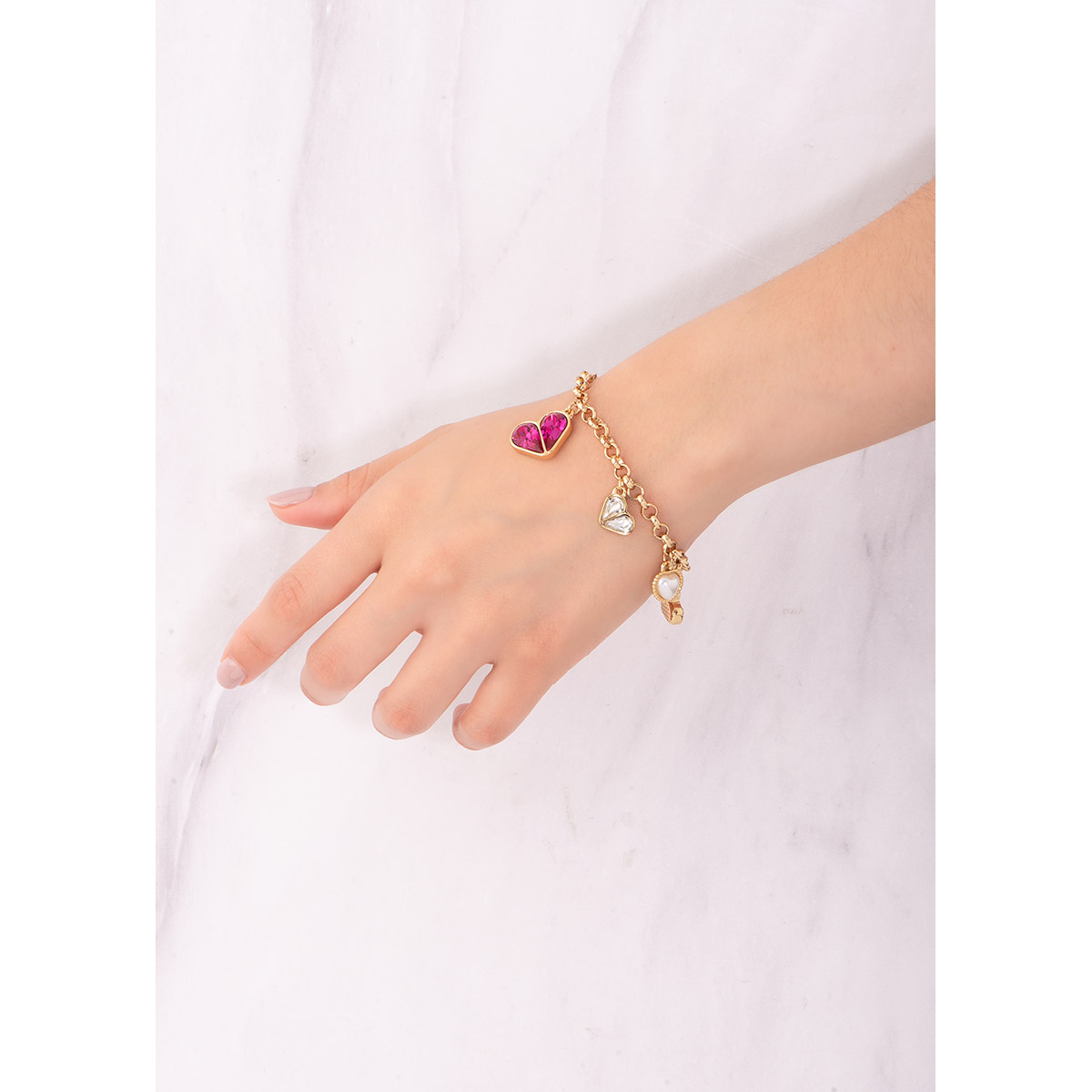 Exquisita pulsera de nuestra colección Paris By NICE. En baño de 18k, con diferentes dijes en forma de corazón, dos con perla en tono crema, dos con piedras en tono cristal y uno con piedras en tono fucsia.
-        Pulsera 18 cm + 2 cm ext.
-         Baño de oro 18k
-        Piedras en tono cristal y fucsia
-        Perla en tono crema
-        Colección Paris By NICE