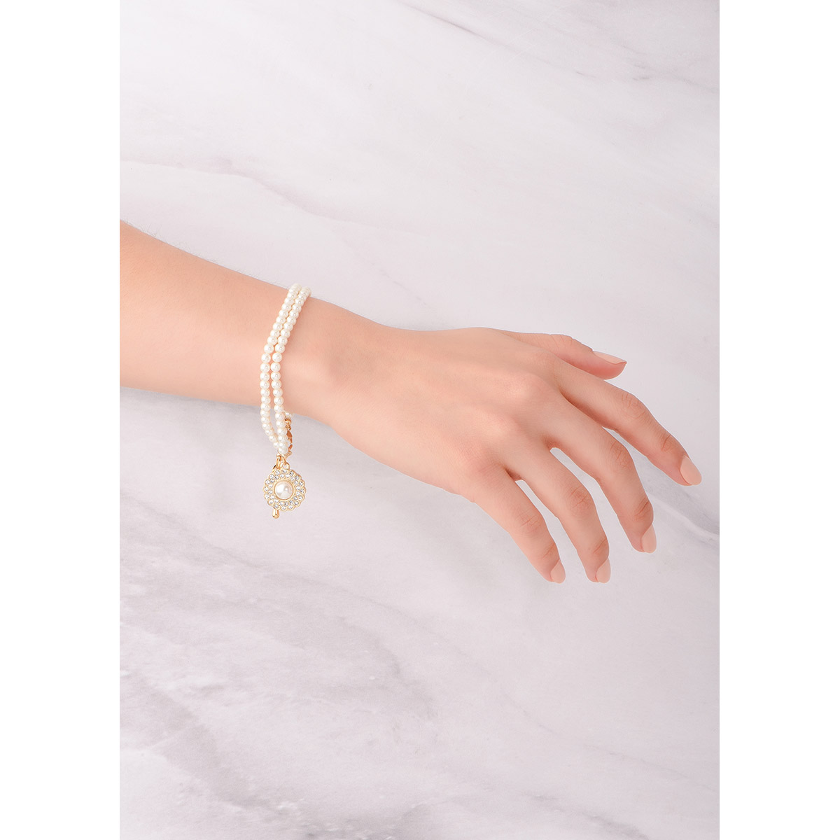 Elegante pulsera en baño de oro, rodeada de perlas en tono crema y piedras en tono cristal, con un magnifico dije en forma floral, incrustado con brillantes piedras en tono cristal y al centro una perla en tono cream.
-        Pulsera 
-        18 cm + 2cm ext.
-        Baño de Oro 18k
-        Perlas en tono cream
-        Piedras en tono cristal 
