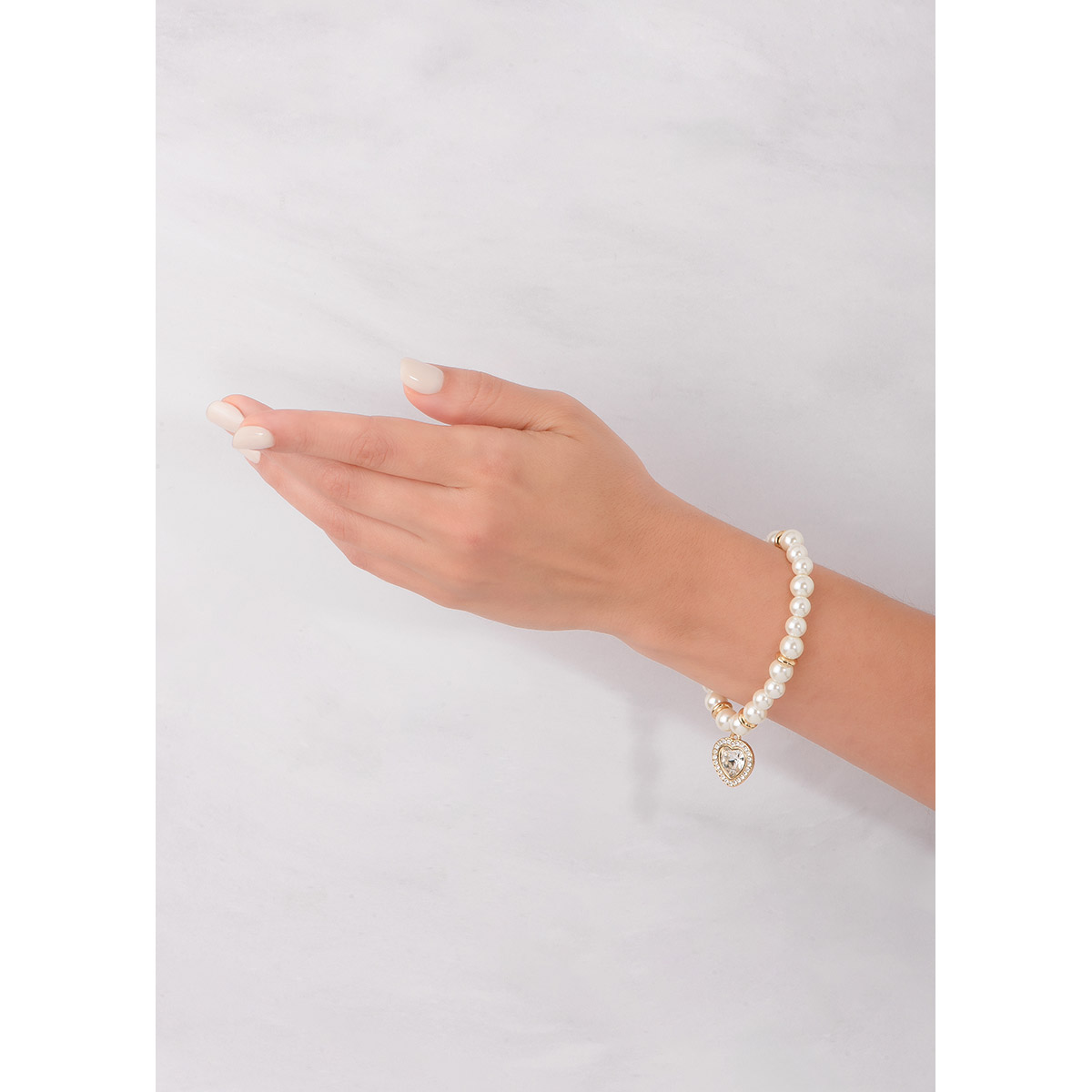 Pulsera incrustada con perlas en tono cream. Con aros en baño de oro y un dije al centro en forma de corazón. El corazón está rodeado por un halo de pequeñas piedras en tono cristal. Combínala con tu collar y aretes.
-        Pulsera
-        Medida única
-        Baño de Oro 18k
-        Perlas en tono cream
-        Piedras en tono cristal
