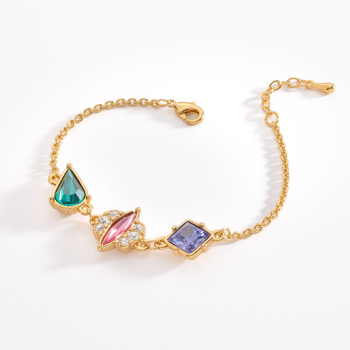 Vibrante pulsera con tres piedras en forma de gota, marquise y cuadrada. Cada una está incrustada en diferentes tonos de colores: aqua en forma de gota, rosa marquise con pequeñas piedras en tono cristal, y una morado de corte cuadrado. 
-        Pulsera 
-        18 cm + 2 cm ext.
-        Baño de Oro 18k
-        Piedras en tono morado, rosa, cristal y aqua
