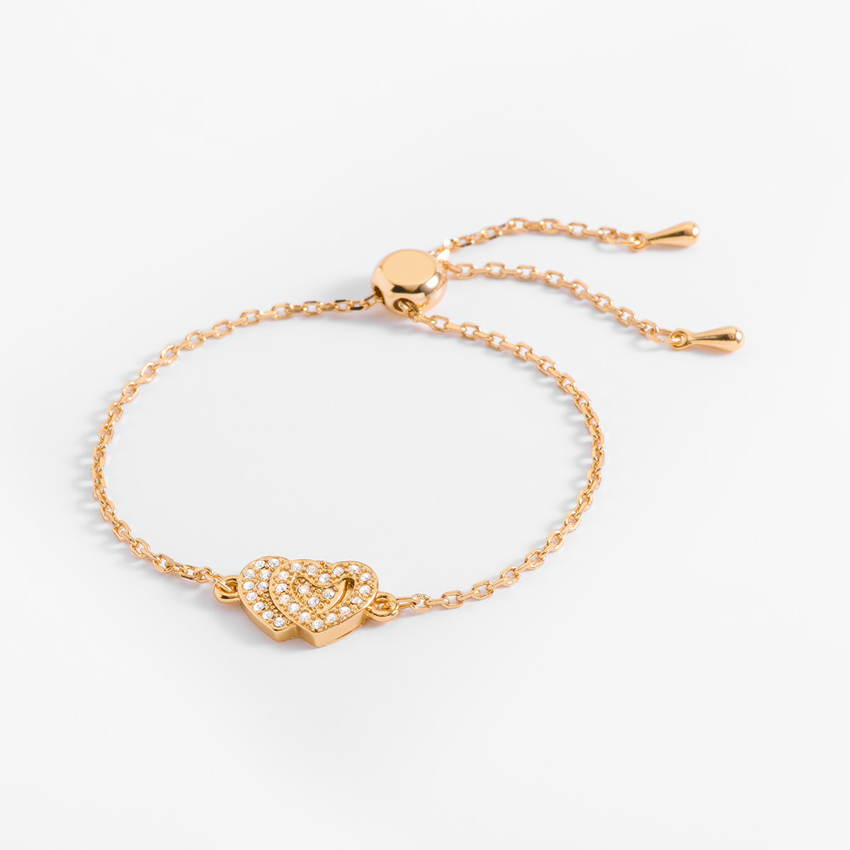 Agrégale amor a tus días con esta pulsera, en baño de oro y con un dije en forma de corazón doble. En el diseño del doble corazón se encuentran incrustadas piedras en tono cristal. Combínalo con tu collar.
-        Pulsera
-        Medida ajustable
-        Baño de Oro 18k
-        Piedras en tono cristal 
