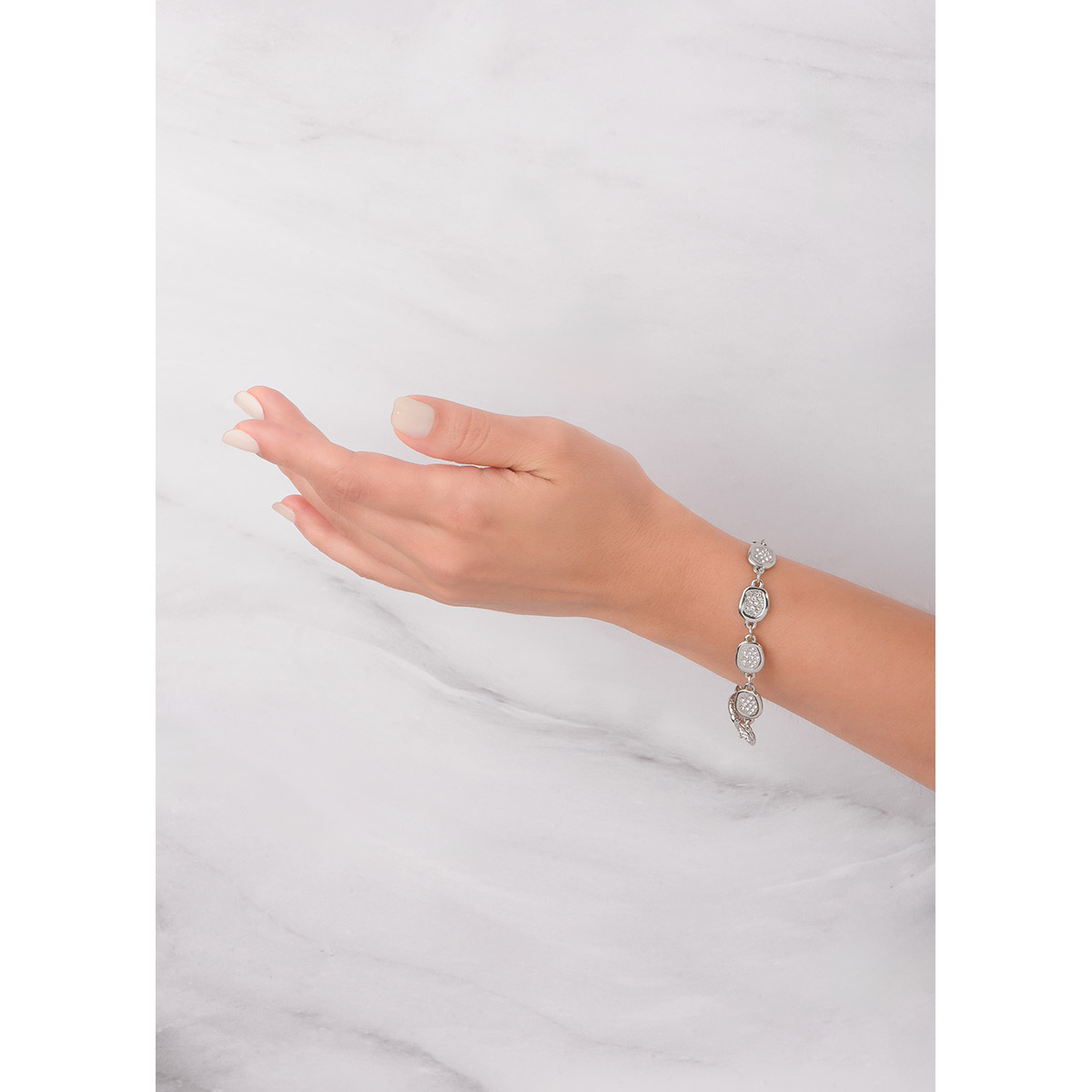 Pulsera en baño de platino, con nueve dijes de diferentes tamaños asimétricos, cada uno incrustado con piedras en tono cristal. Complementa tu set con el collar y aretes.
-        Pulsera
-        18 cm + 2 cm ext.
-        Baño de Platino
-        Piedras en tono cristal
