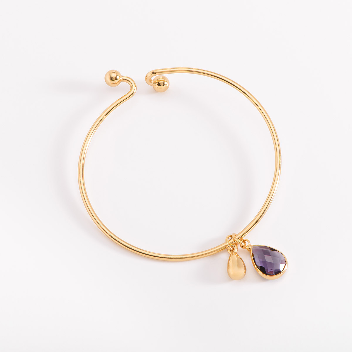 Pulsera en baño de oro, de medida única, se destaca por sus dos dijes colgantes, uno piedra en tono morado en forma de lágrima y otra lágrima más pequeña dorada.
-        Pulsera
-        Medida única
-        Baño de Oro 18k
-        Diamonice™ en tono cristal
