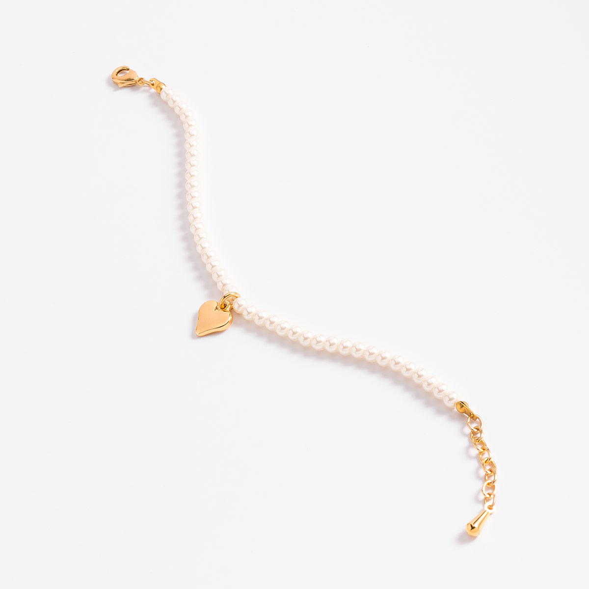 Pulsera con perlas en tono crema y dije de corazón en baño de oro ideal para realzar tu estilo y aportar un toque sofisticado a tu look diario.