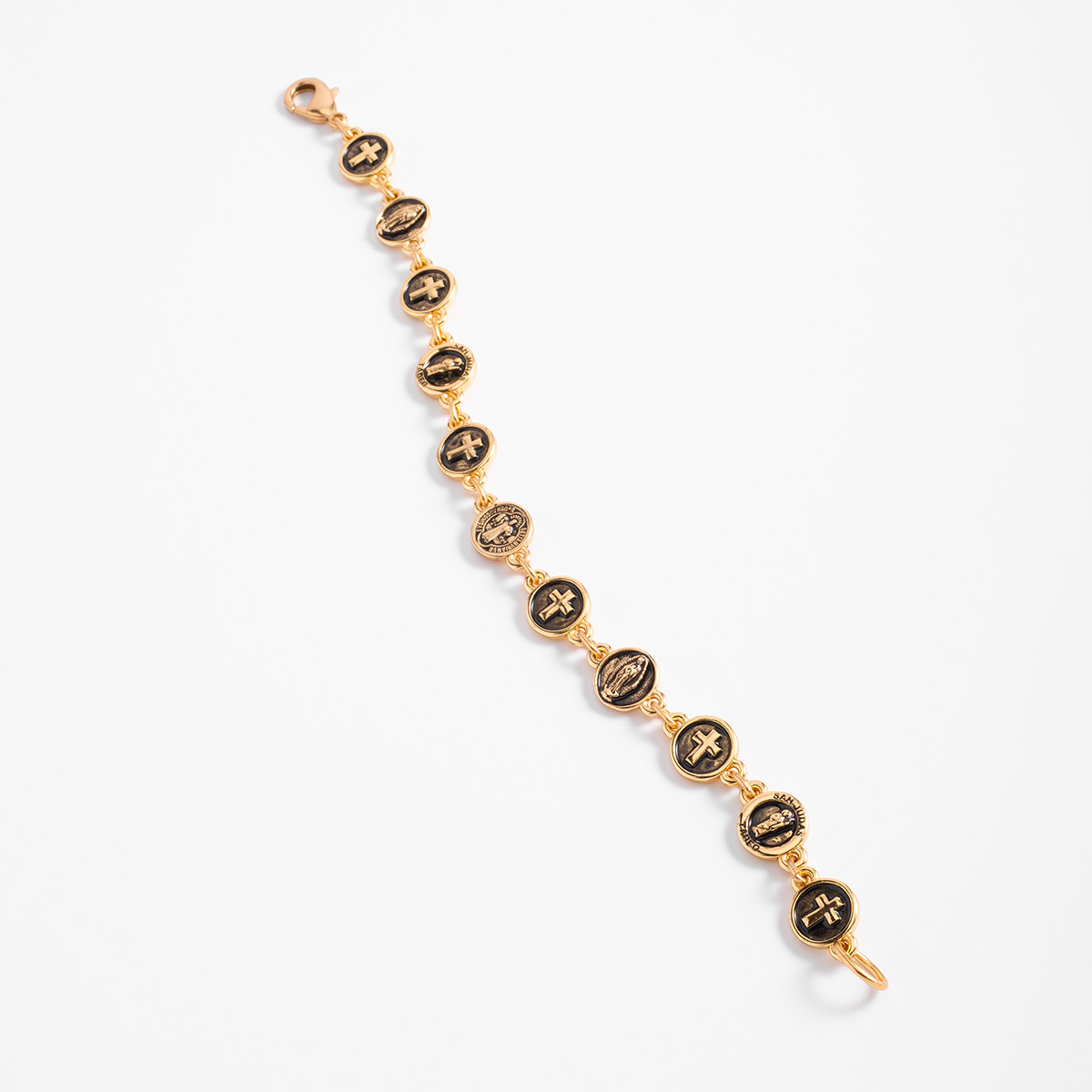 Pulsera en baño de oro y negro con dijes circulares de cruces y motivos religiosos