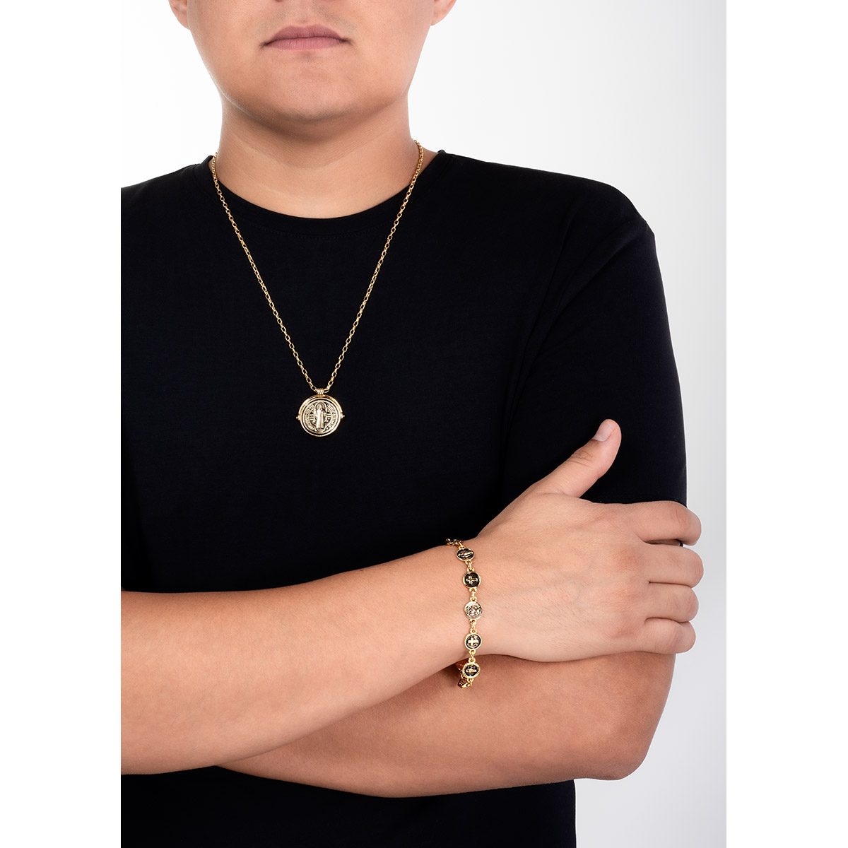 Pulsera en baño de oro y negro con dijes circulares de cruces y motivos religiosos