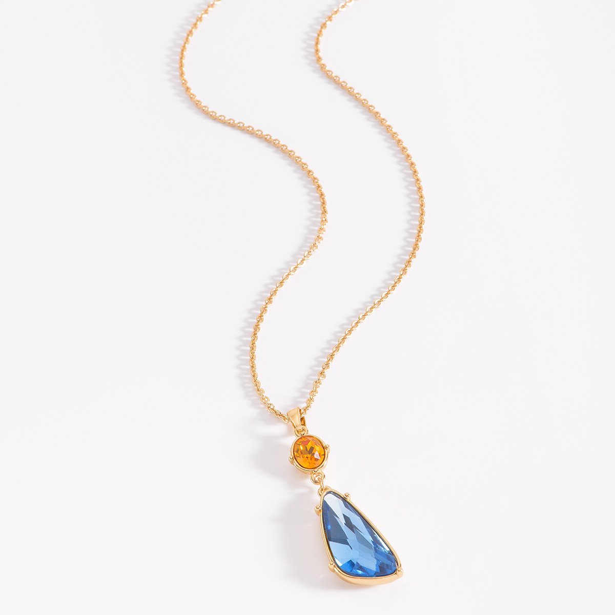 La fusión de piedras en tono ámbar y azul convergen en este collar en baño de oro. El diseño se centra en un dije de dos piedras perfectamente equilibradas: una lágrima de cristal en tono azul que cuelga bajo una piedra en tono ámbar circular. Combínalo con tus aretes.
-        Collar
-        52 cm + 10 cm ext.
-        Baño de Oro 18k
-        Piedras en tono azul y ámbar
