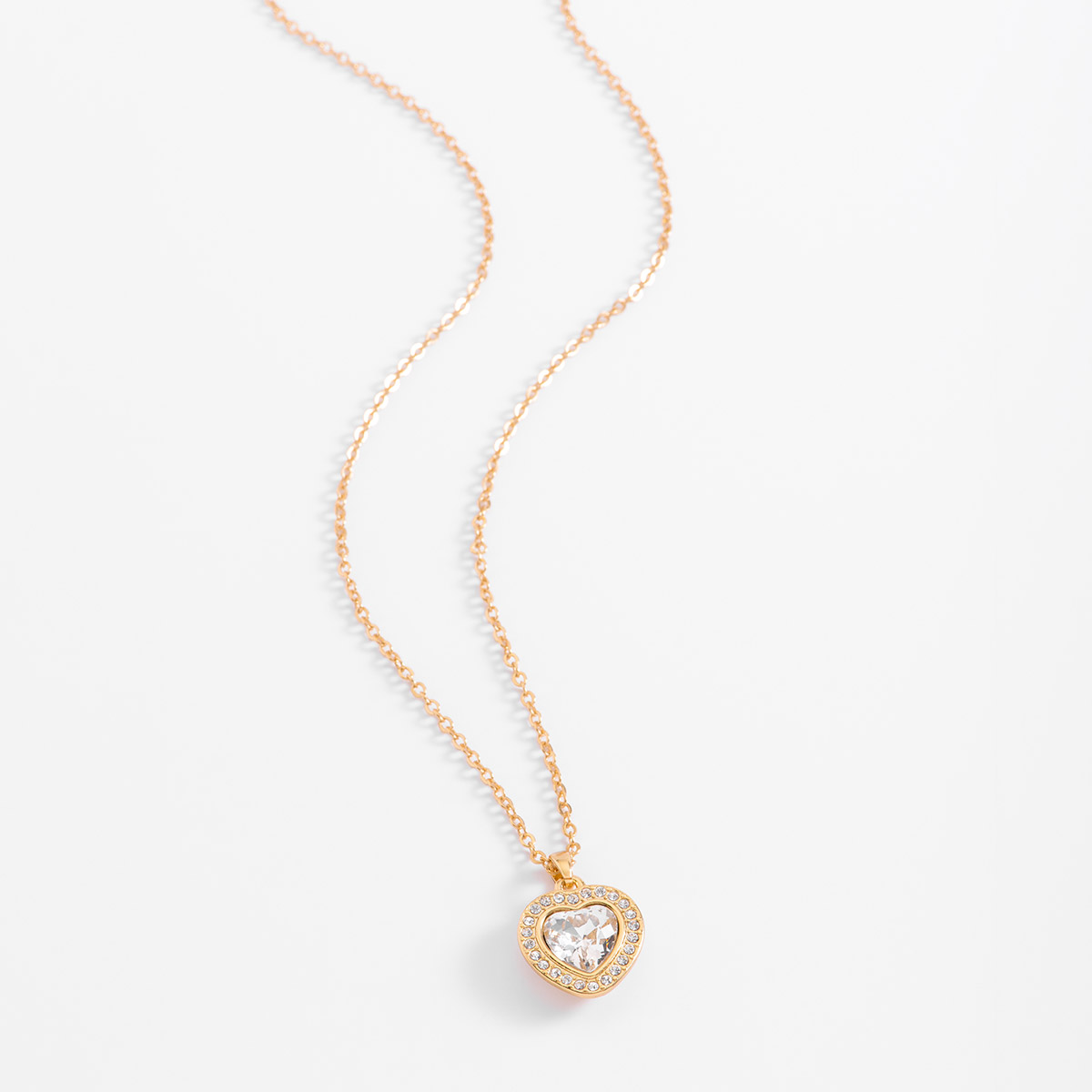 El diseño romántico se conjuga en este collar de baño de oro, con un dije en forma de corazón de donde resalta una piedra al centro de la forma, rodeada de pequeñas piedras en tono cristal. Combínalo con tus aretes y pulsera.
-        Collar
-        45 cm + 10 cm ext.
-        Baño de Oro 18k
-        Piedras en tono cristal

