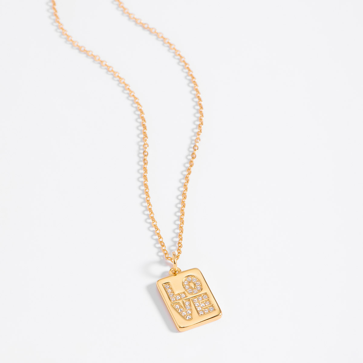 Moderno collar en baño de oro 18k con un dije colgante rectangular que muestra la palabra LOVE (amor). Cada letra está cuidadosamente decorada con finas piedras en tono cristal que capturan la luz, creando un efecto resplandeciente.  Una joya versátil y emotiva que se convertirá en una pieza esencial en tu colección de accesorios.
-        Collar
-        42 cm + 10 cm ext.
-        Baño de oro
-        Piedra en tono cristal