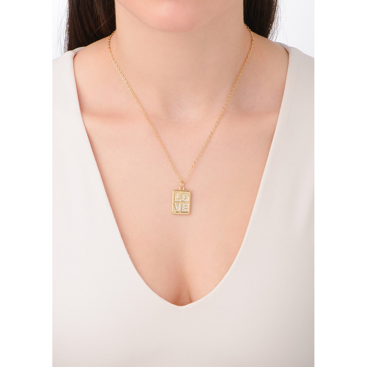 Moderno collar en baño de oro 18k con un dije colgante rectangular que muestra la palabra LOVE (amor). Cada letra está cuidadosamente decorada con finas piedras en tono cristal que capturan la luz, creando un efecto resplandeciente.  Una joya versátil y emotiva que se convertirá en una pieza esencial en tu colección de accesorios.
-        Collar
-        42 cm + 10 cm ext.
-        Baño de oro
-        Piedra en tono cristal