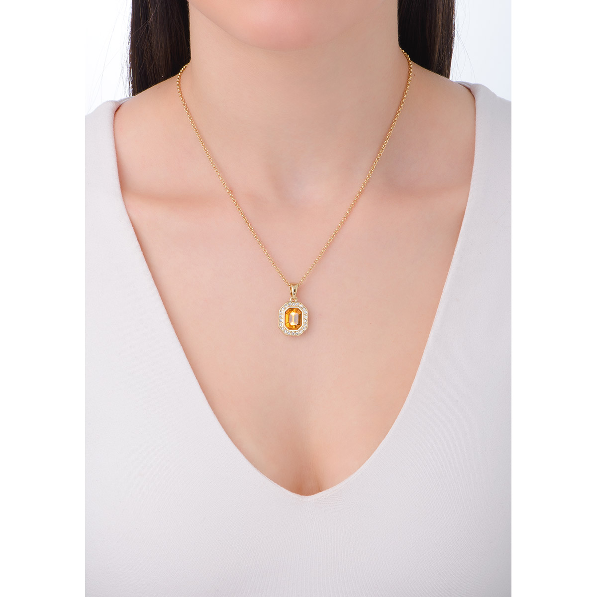 Hermoso y sofisticado collar en baño de oro de 18k, acompañado con una vibrante piedra en tono ámbar en el centro. El Dije está enmarcado por una fila de finas piedras en tono cristal que añaden un destello de lujo y sofisticación. La combinación del cálido tono ámbar con el resplandor del dorado crea un contraste armonioso y atractivo, haciendo de este collar una pieza verdaderamente deslumbrante.                                                                                                        -        Collar
-        40 cm + 10 cm ext.
-        Baño de oro
-        Piedra en tono ámbar y cristal