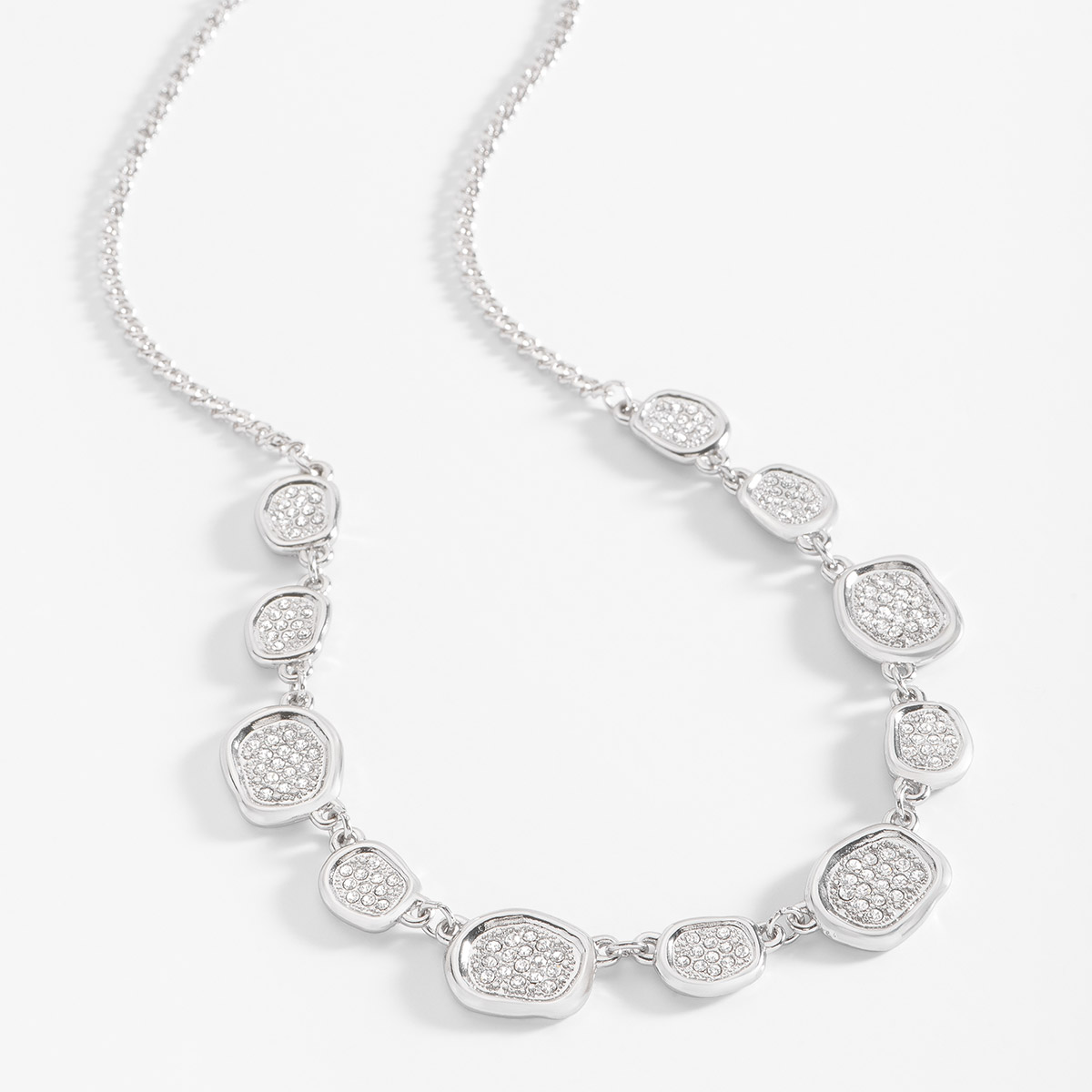 Collar en baño de platino, con diferentes dijes asimétricos, cada uno incrustado con piedras en tono cristal. Completa tu set con los aretes y pulsera.
-        Collar
-        44 cm + 10 cm ext.
-        Baño de Platino
-        Piedras en tono cristal 
