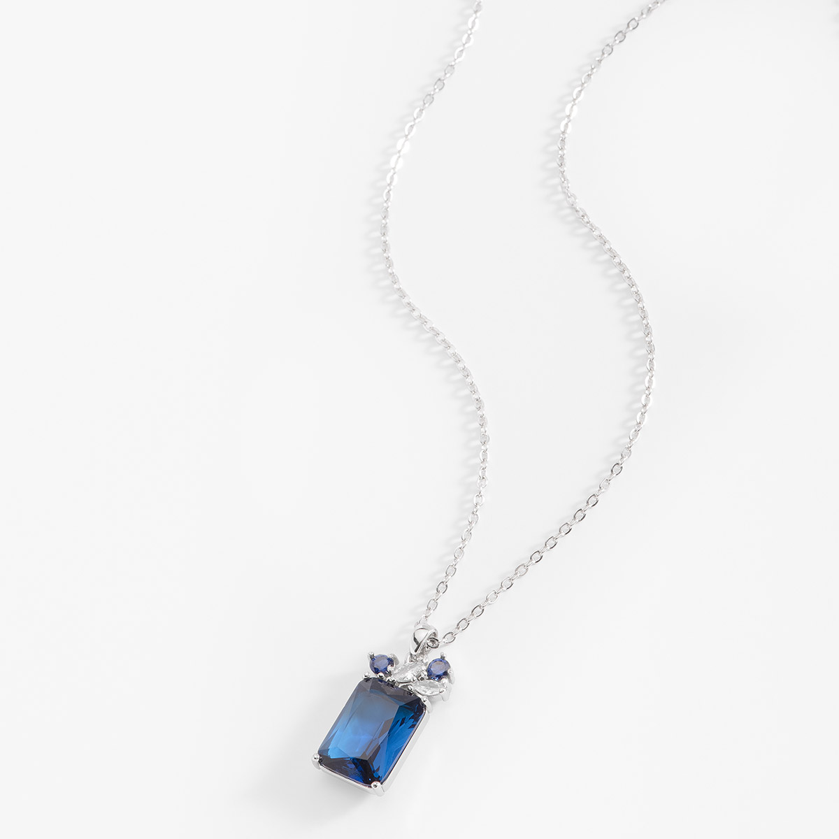 El resplandor del Diamonice™ en tono azul se destaca en este collar en baño de platino. La piedra tiene una forma cuadrangular, y colgando en la parte superior se encuentran cuadro pequeñas piedras Diamonice™, dos en tono azul y dos en tono cristal. Combínalo con tus aretes y anillos.
-        Collar
-        40 cm + 10 cm ext.
-        Baño de Platino
-        Diamonice™ en tono azul y cristal
