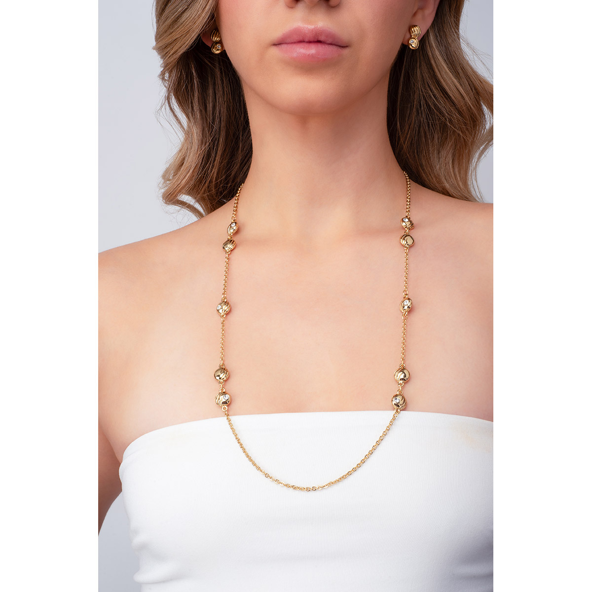 Cadena en baño de oro, que diseña un collar de esferas con líneas texturizadas, y con piedras en tono cristal incrustadas.
-        Collar
-        70 cm + 10 cm ext.
-        Baño de Oro 18k
-        Piedras en tono cristal 