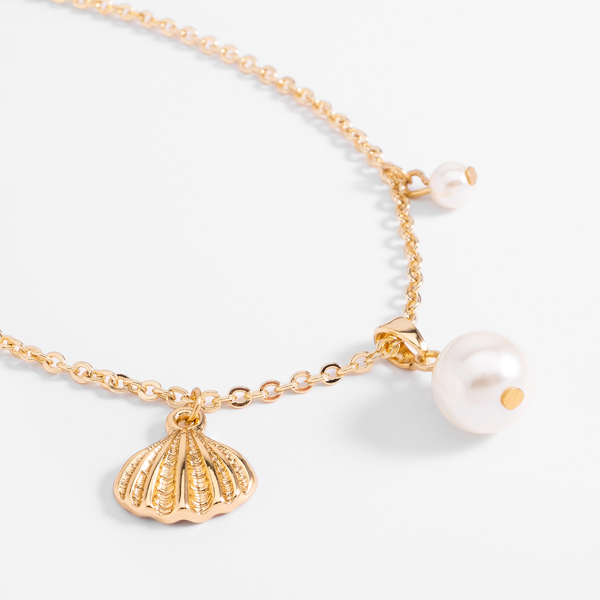 Collar en baño de oro con dije de concha y perlas sintéticas