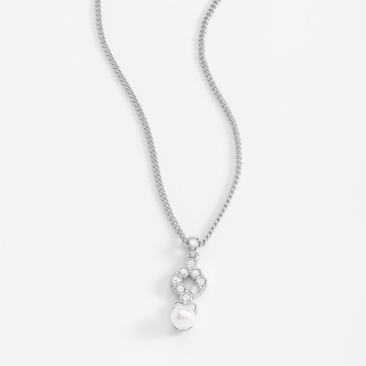Deslumbrante collar en baño de platino, acompañado con piedras en tono cristal y una reluciente perla en tono cream. 
-Collar con Dije
-40 cm + 10 cm ext.
-Platino