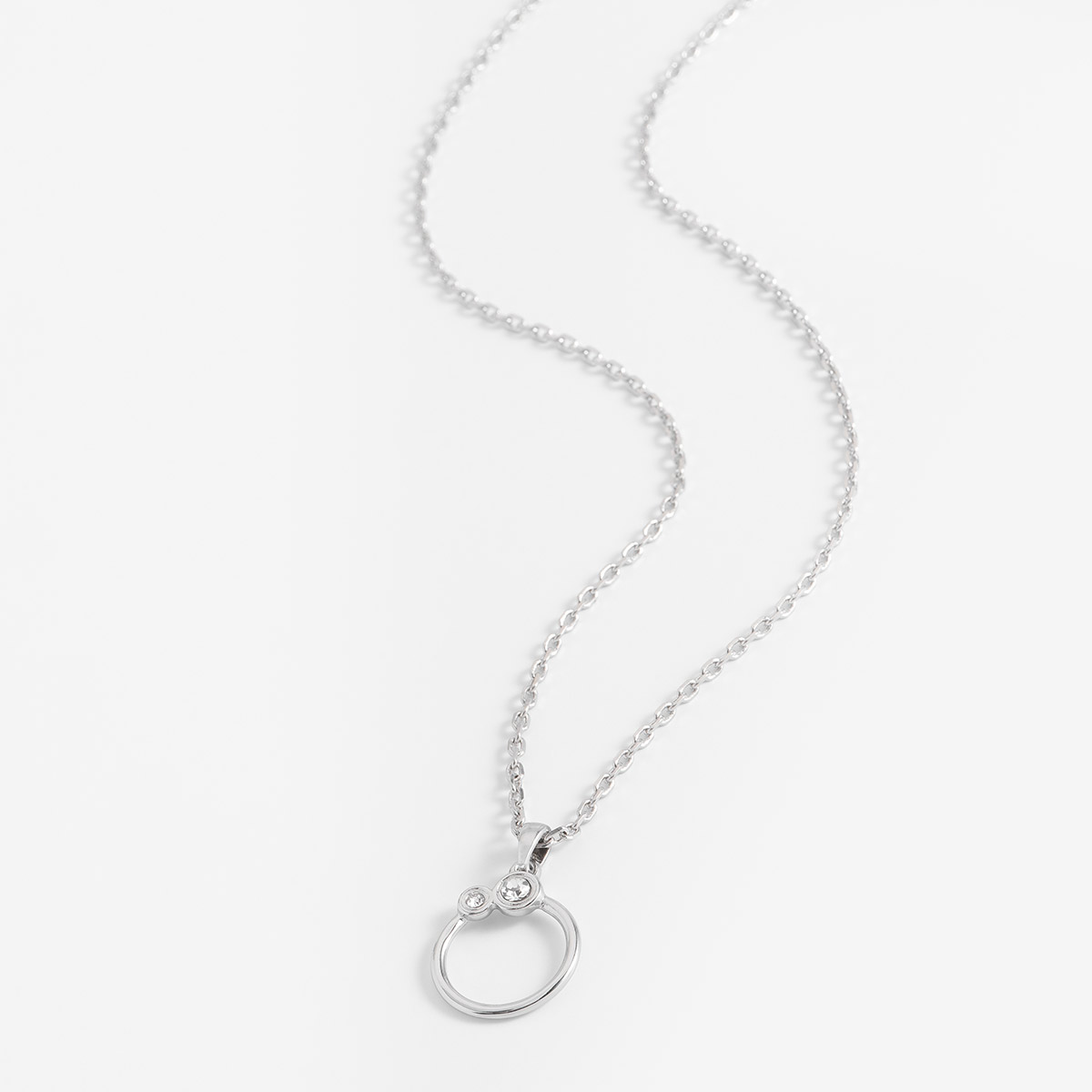 Hermoso collar con dije circular en baño de platibo, incrustado con dos piedras en trono cristal de diferentes tamaños.
-        Collar con dije
-        42 cm + 10 cm ext.
-        Baño de Platino
-        Piedras en tono cristal
