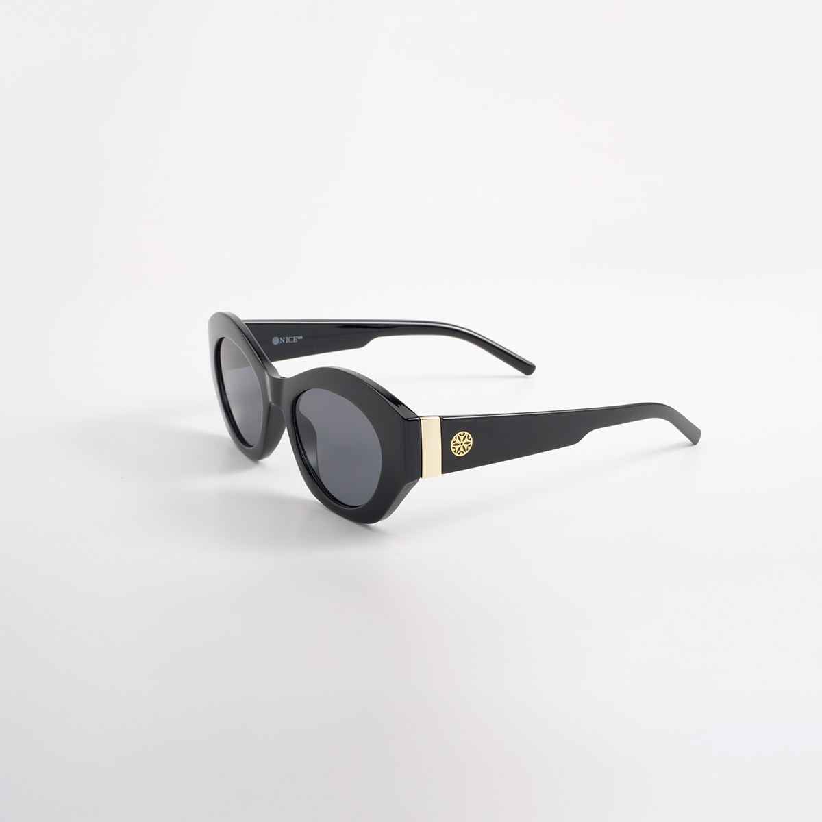 Lentes de sol negros con silueta cat eye y detalles dorados contemporáneos
